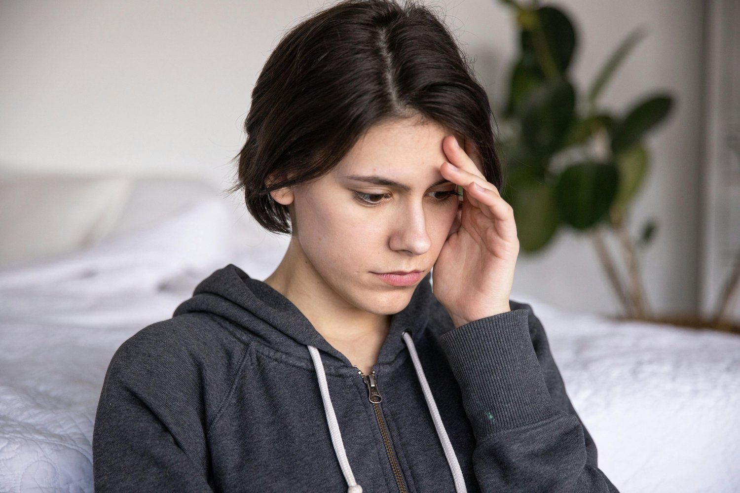 Young woman looking down with her hand to her forehead