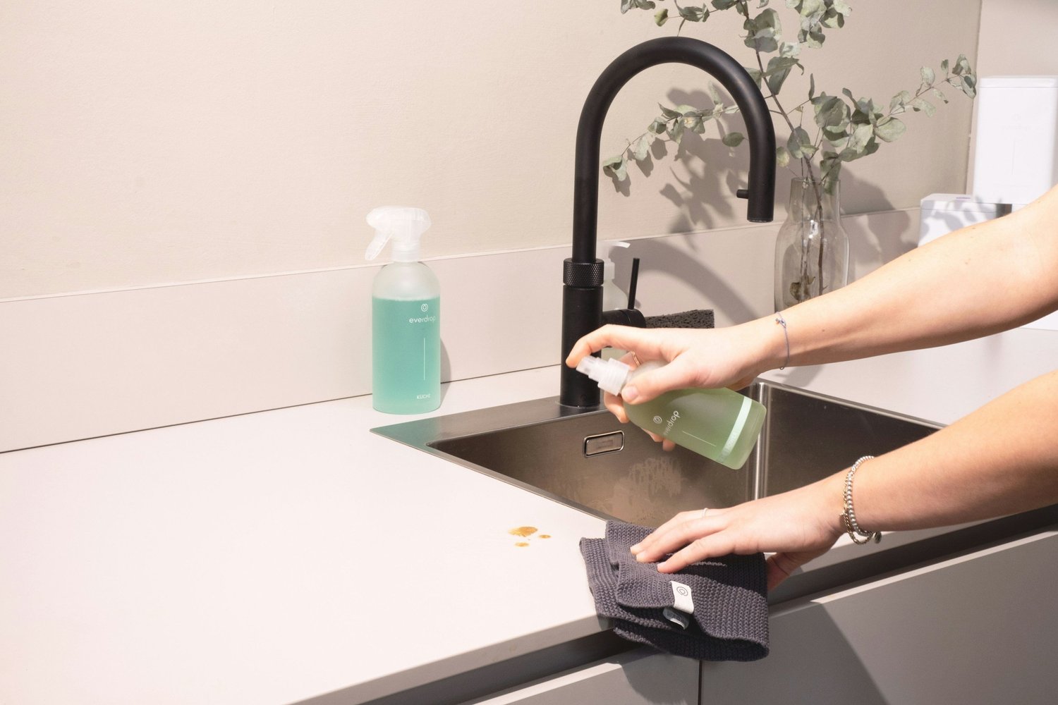 Person washing and wiping a kitchen sink as part of everyday household care, supporting OCD awareness education