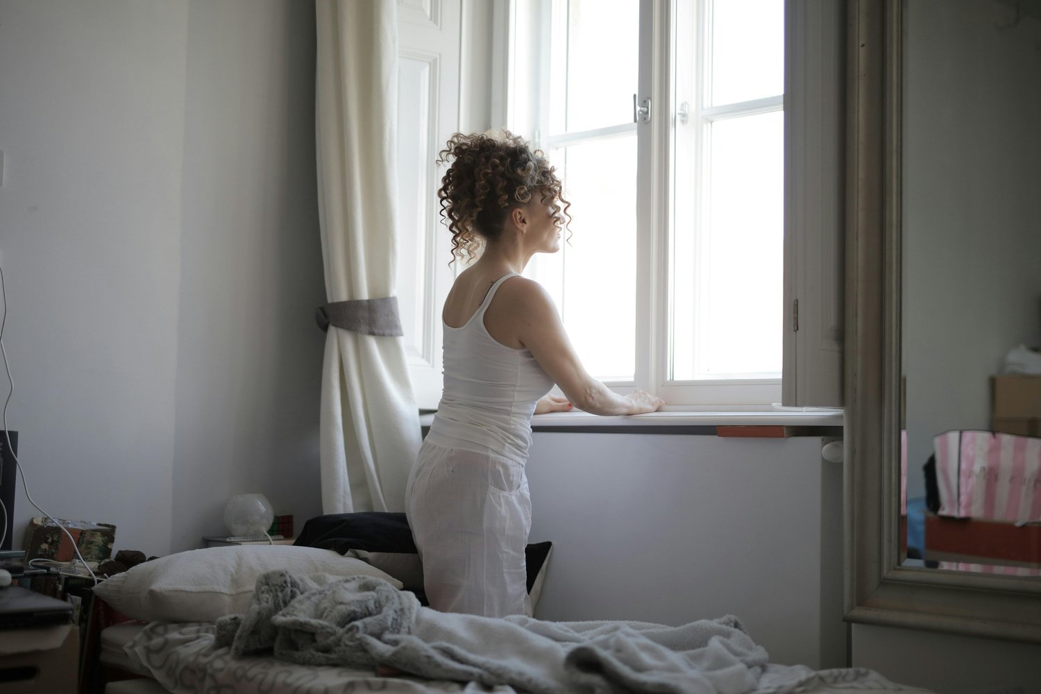 A calm woman reflecting by a window with soft natural light, symbolizing healing and mental wellness in Arizona.