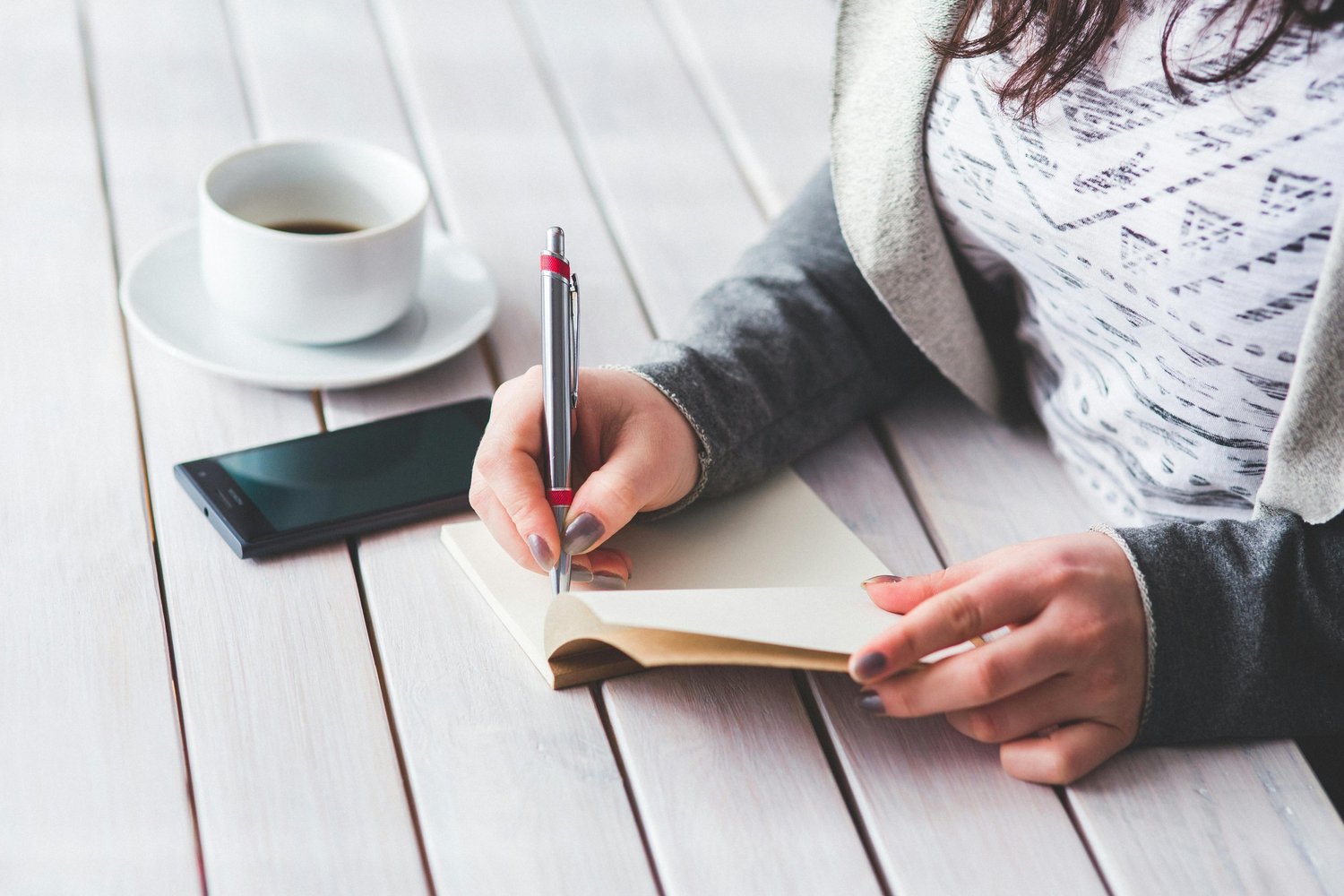 An open notebook and journal on a table with a cup of tea, symbolizing mindfulness and self-reflection in mental wellness.