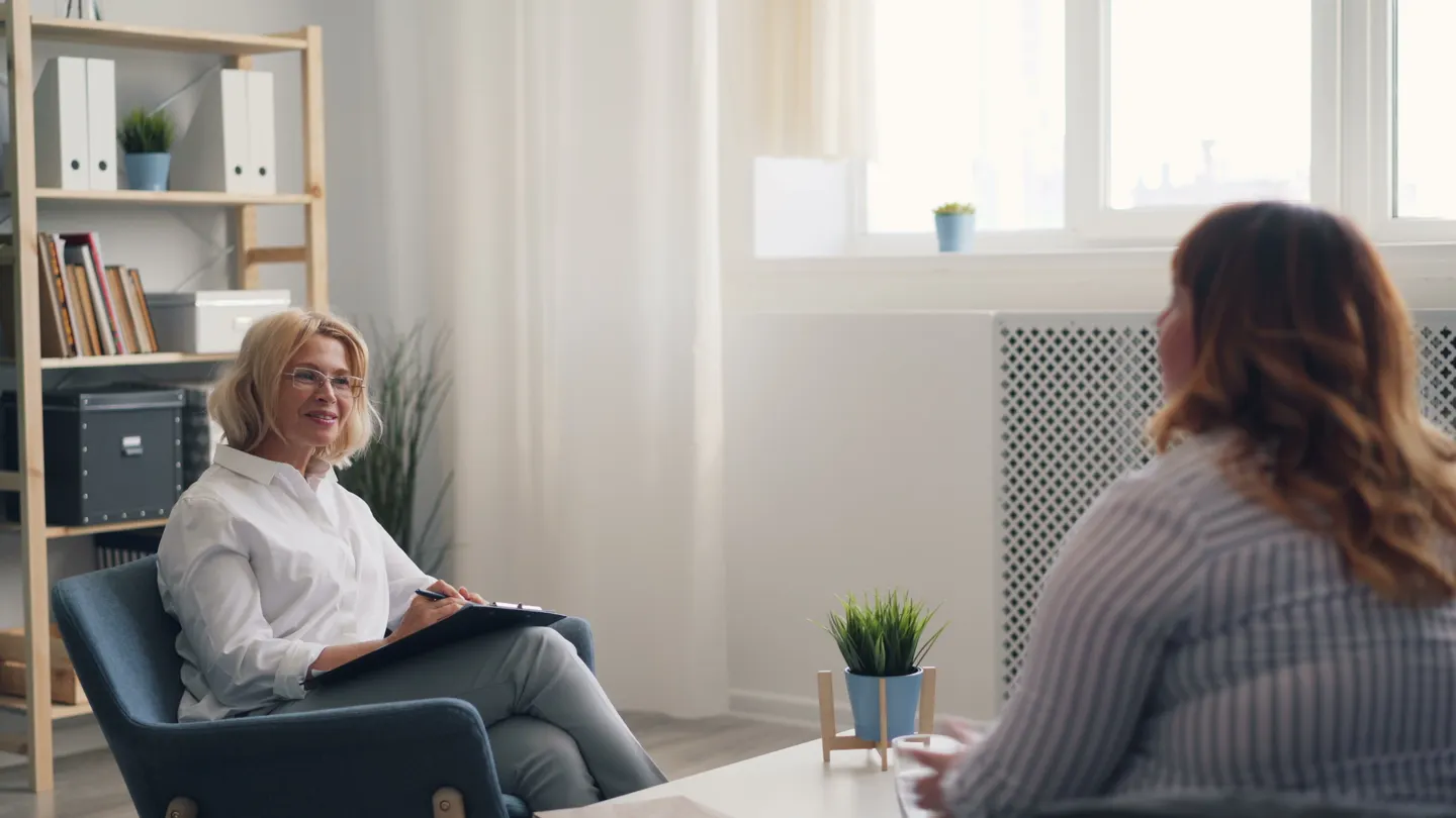 A therapist and client speaking face to face in a bright counseling office