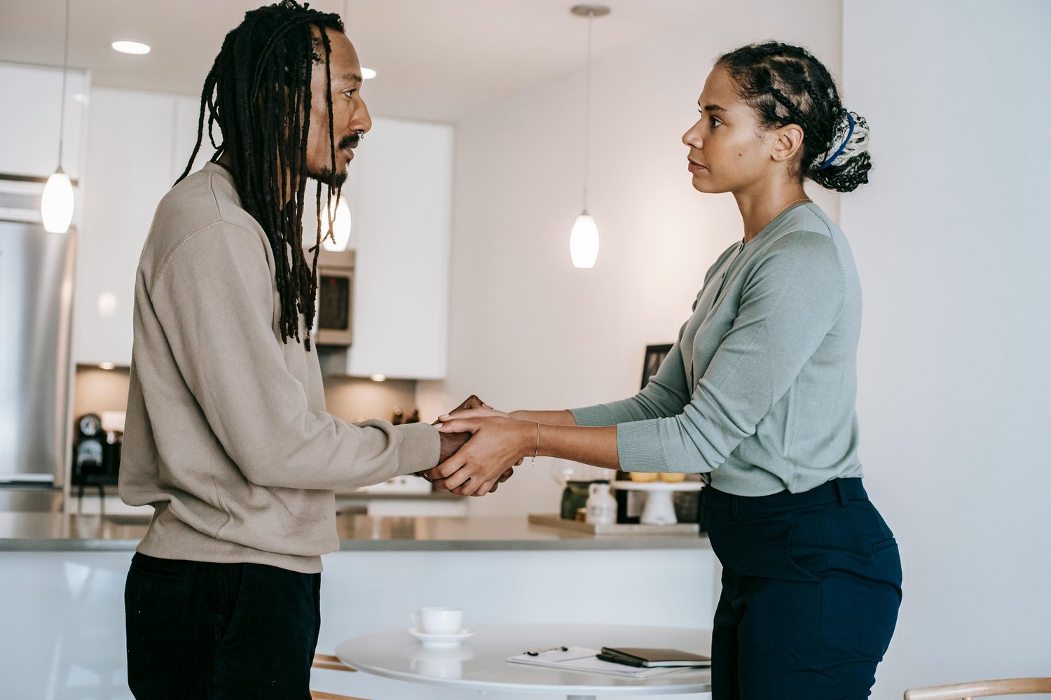 Two people holding hands while talking face to face