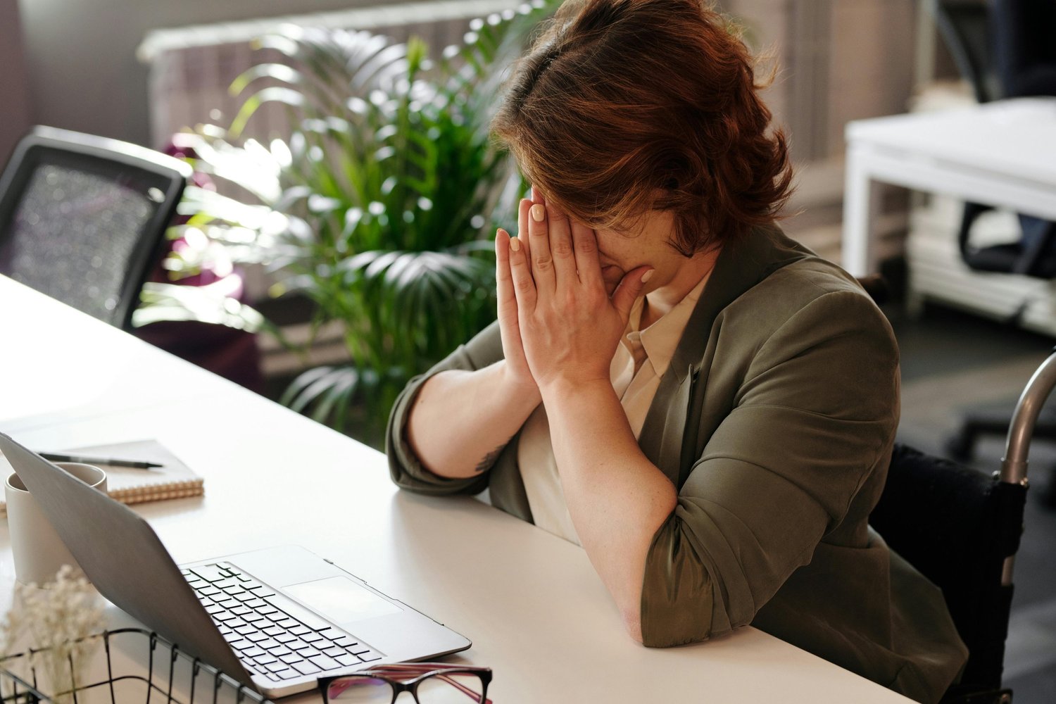Woman sitting at her desk looking stressed and anxious, overwhelmed by work, illustrating anxiety and mental health challenges.