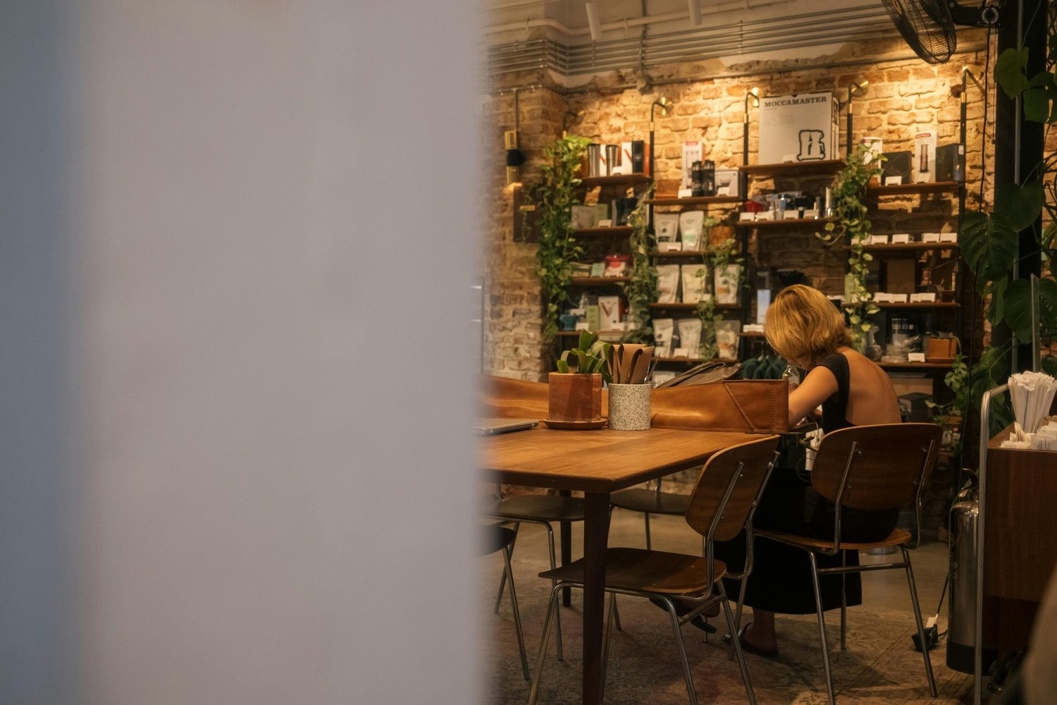 Woman sitting alone in a cozy coffee shop, staring thoughtfully at her drink, appearing deep in thought or anxious.