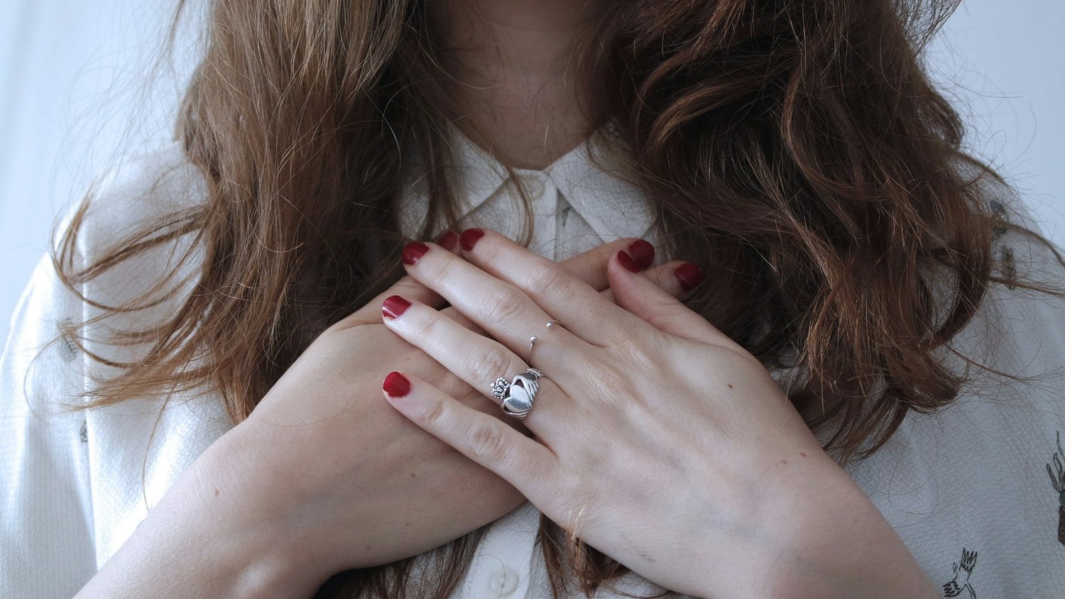 Woman placing her hands gently on her chest with a calm, relieved expression, symbolizing emotional healing, self-compassion, and inner peace.