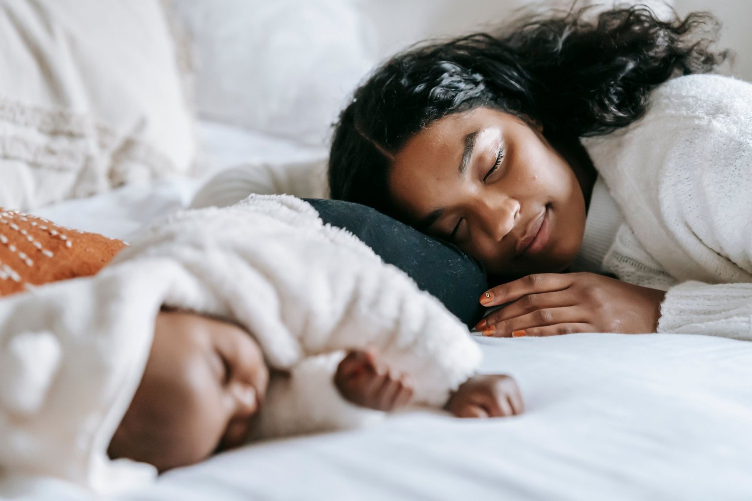 Mother and baby sleeping peacefully in bed, representing postpartum mental health support and rest for new parents.