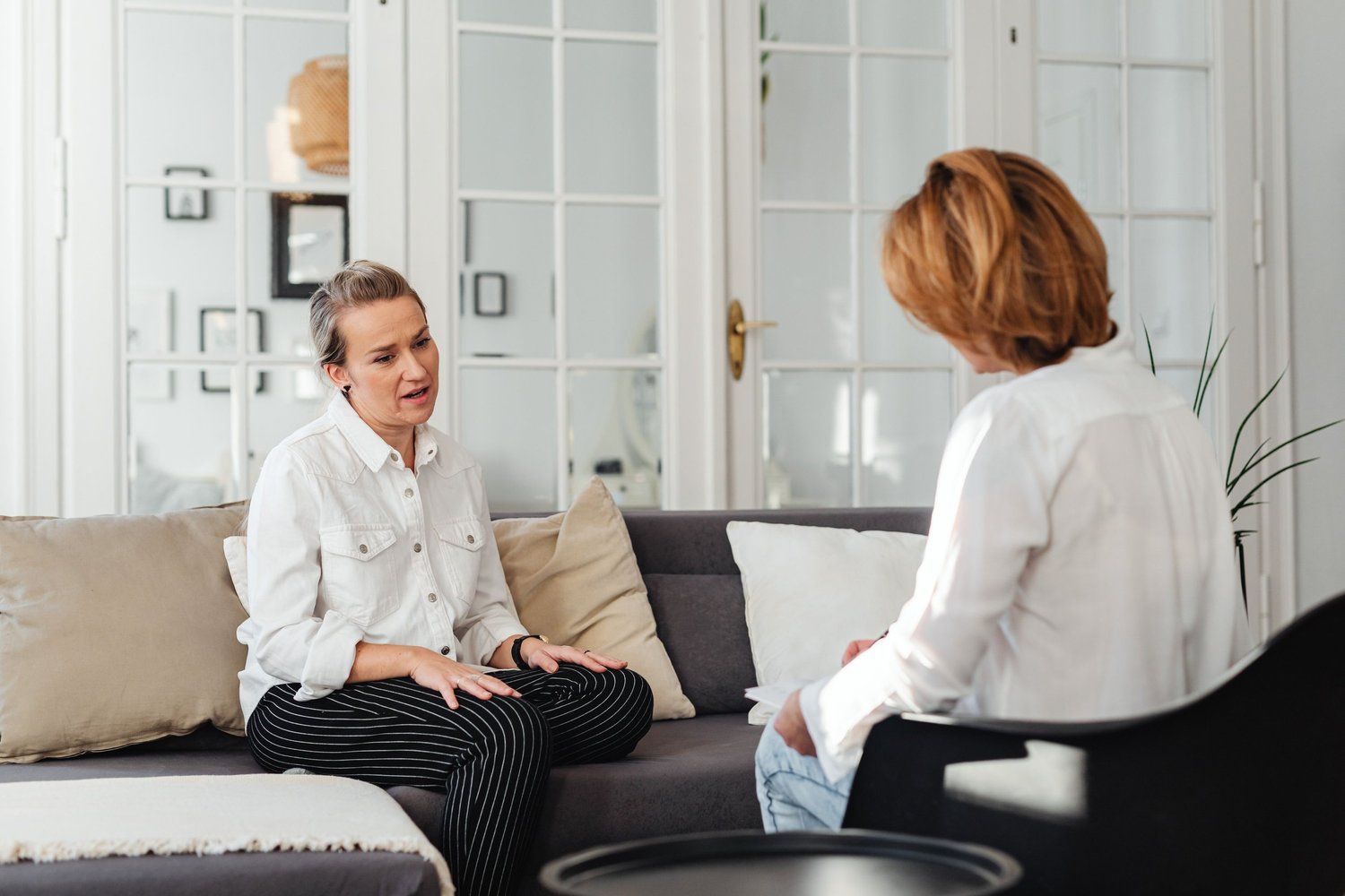 Two women talking on a sofa in a counseling session