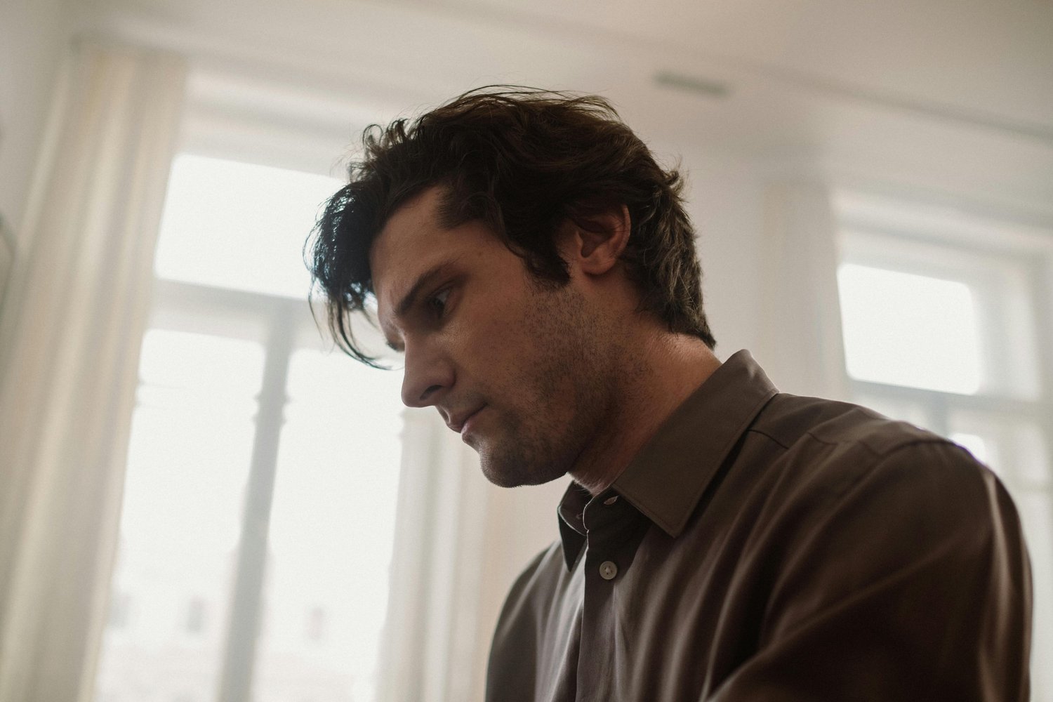 A man sits quietly with a pensive expression, lost in deep thought as intrusive thoughts and anxiety occupy his mind.