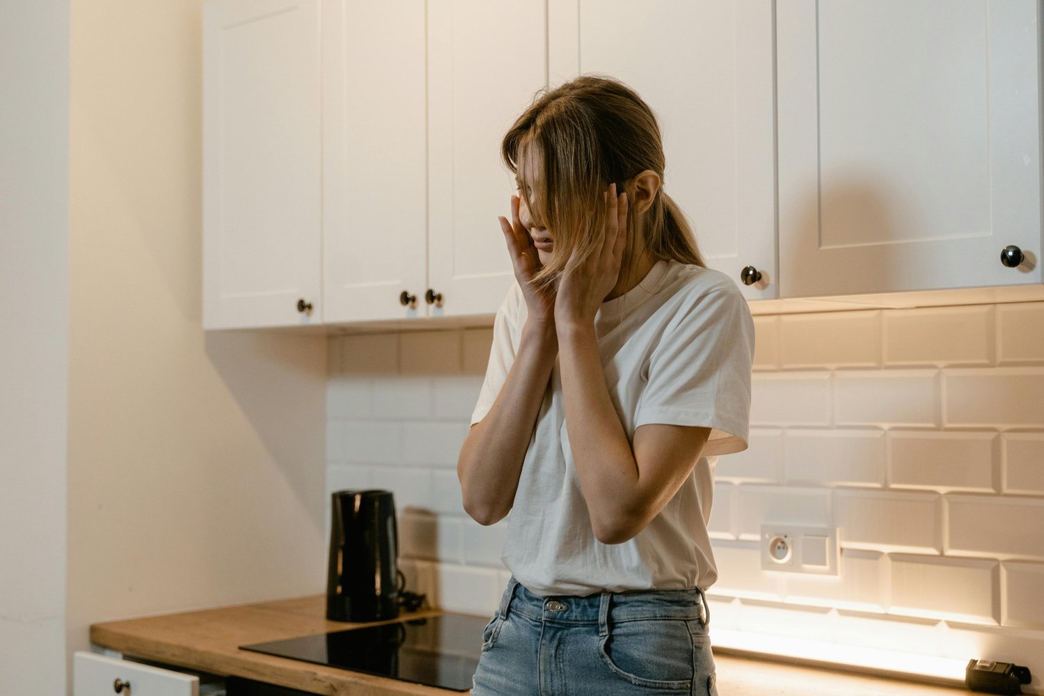 Woman holding her head in their hands, illustrating the emotional strain of mental overwhelm and anxiety.
