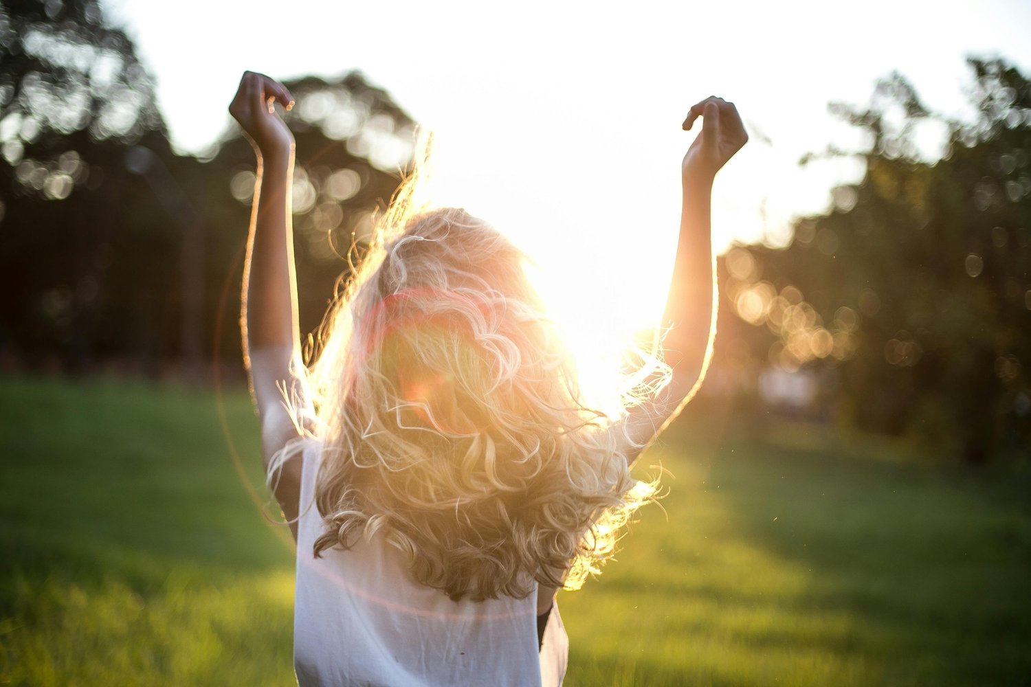 Person outdoors lifting their arms in the sunlight