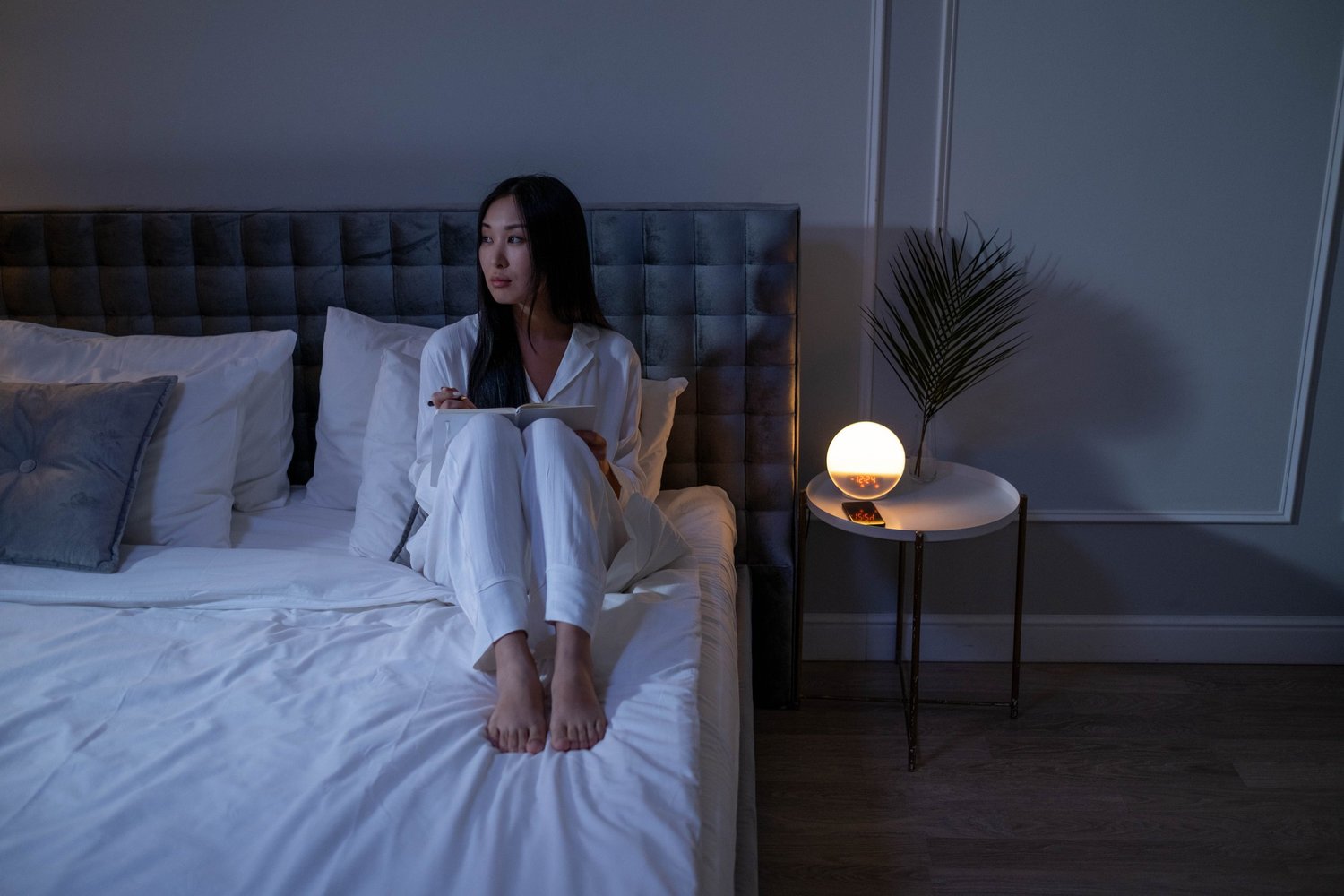 Woman sitting awake on her bed at night while experiencing intrusive thoughts and nighttime OCD